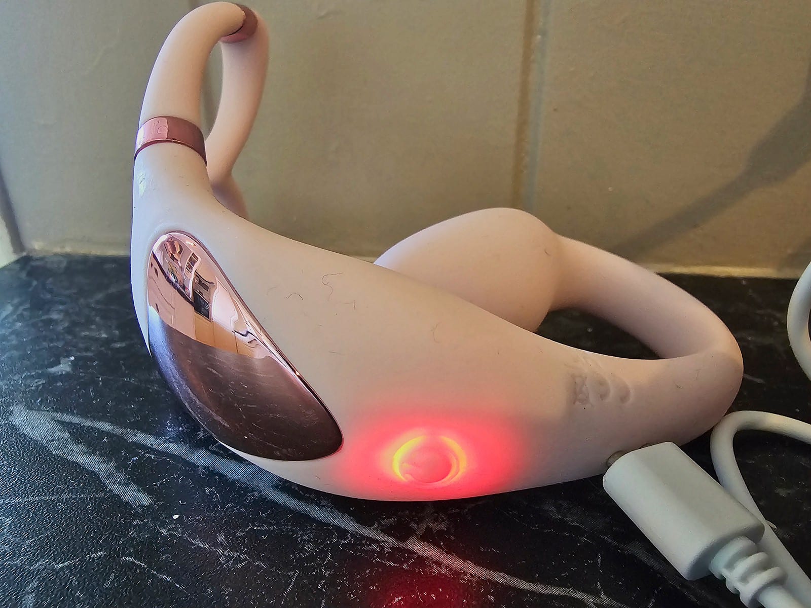 Venus on its magnetic charger with the red charging light on
